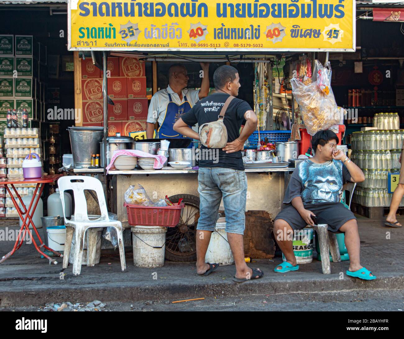 AYUTTHAYA, THAÏLANDE, 27 JANVIER 2020, le vendeur dans la rue offre de la nourriture thaïlandaise - nouilles fries avec du porc et une bière trempée dans la sauce. Banque D'Images