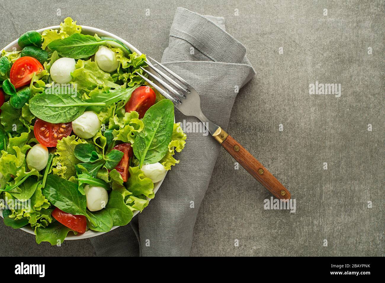 Salade de laitue verte saine avec tomate et mozzarella sur fond de table gris Banque D'Images