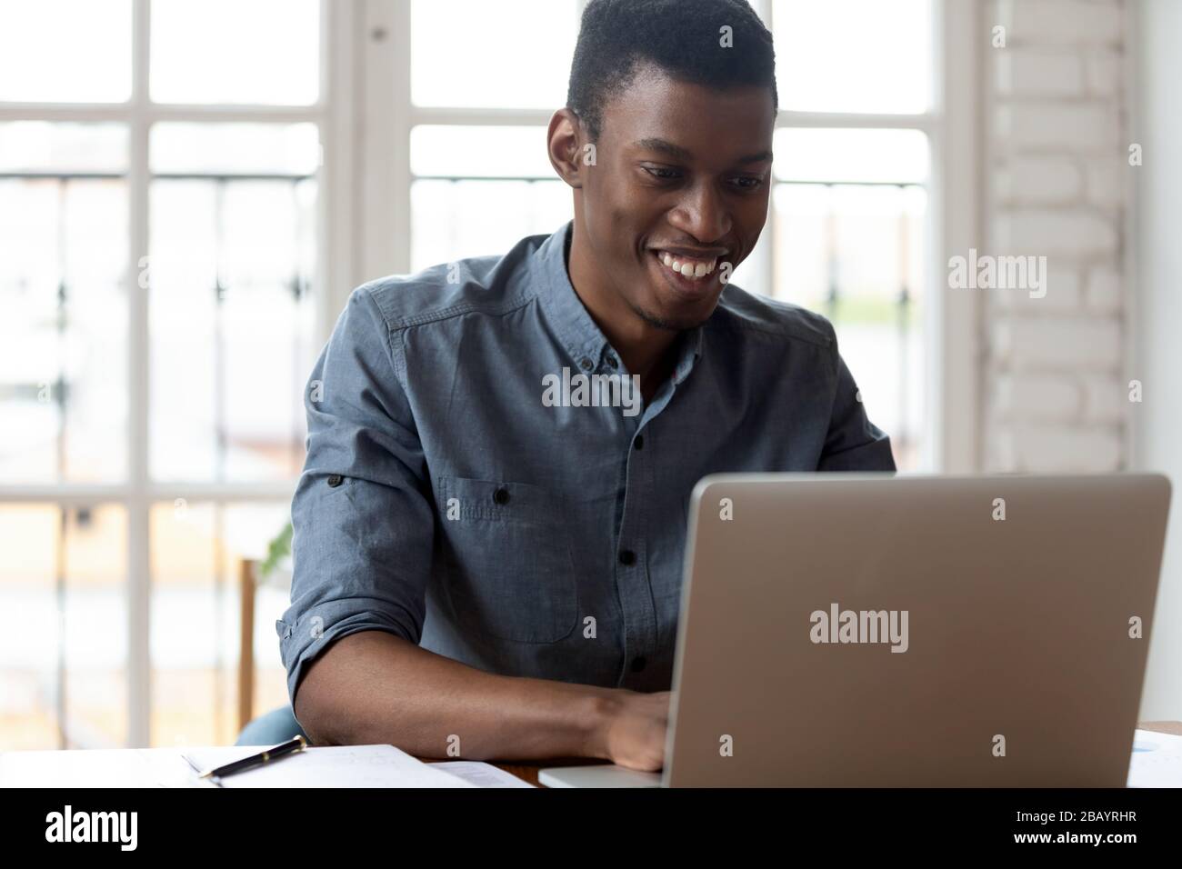 Employé de bureau africain assis sur le lieu de travail en tapant sur l'ordinateur portable Banque D'Images