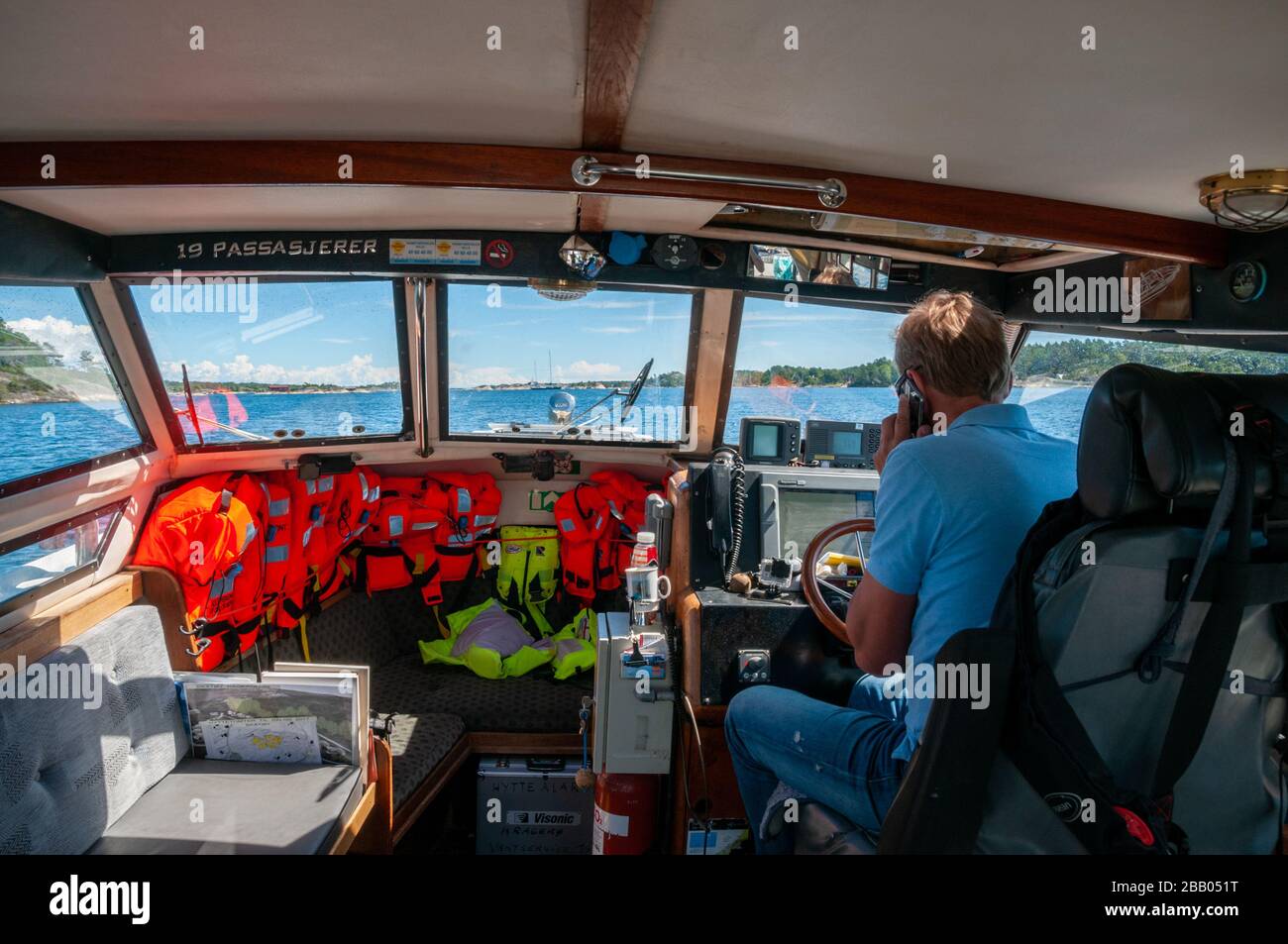 Un capitaine de bateau-taxi sur son téléphone mobile alors qu'il navigue entre les îles de l'archipel de Kragerø sur la côte sud de la Norvège. Banque D'Images