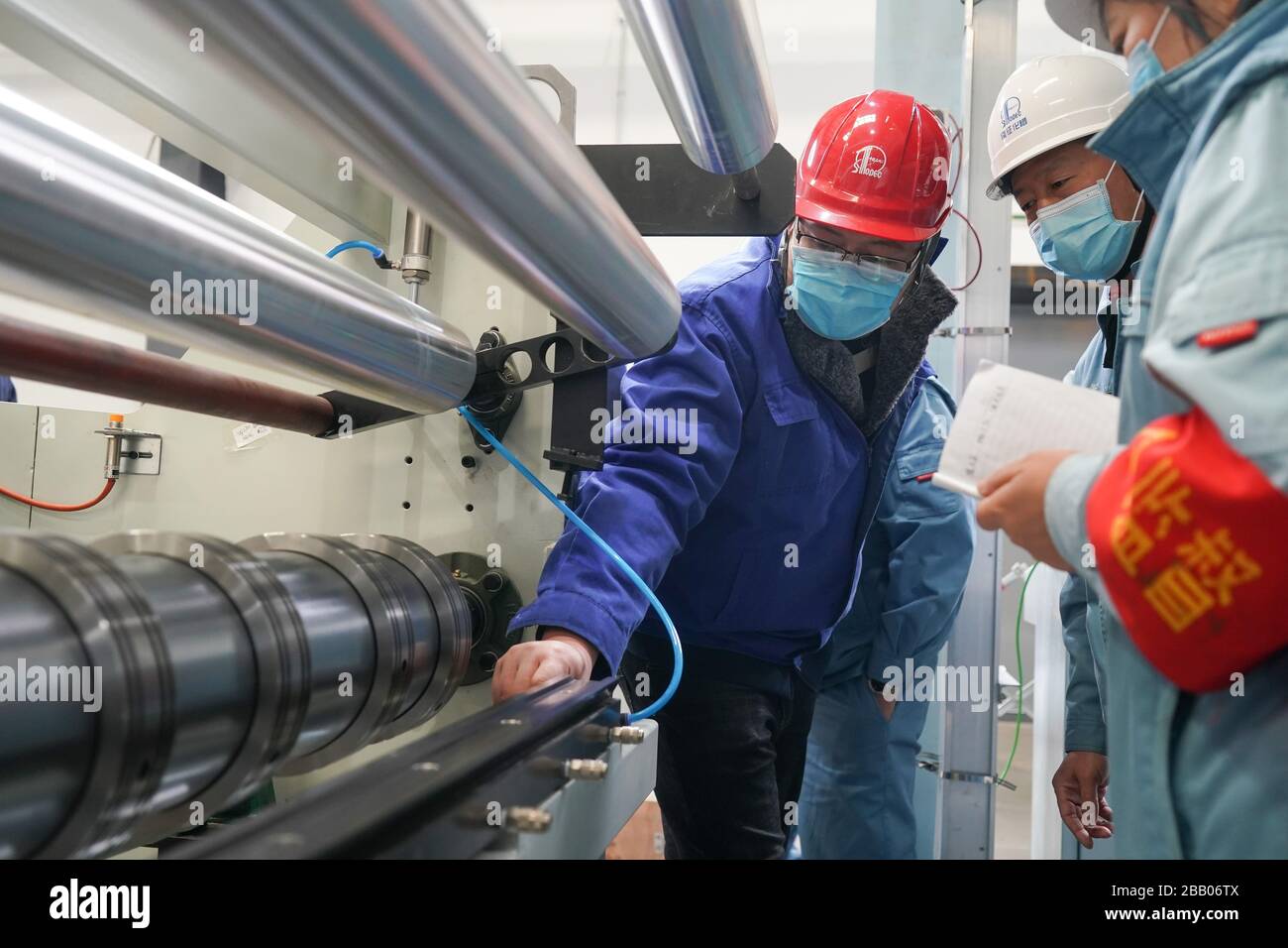 (200330) -- NANJING, 30 mars 2020 (Xinhua) -- les travailleurs se préparent à l'exploitation de la première chaîne de production de tissu non tissé fondu, un matériau clé pour masques, dans une usine de Sinopec, à Yizheng, dans la province de Jiangsu en Chine orientale, 27 mars 2020. La première ligne de production a commencé à fonctionner le 29 mars, produisant quotidiennement plus d'une tonne de tissu non tissé fondu, qui peut être transformé en un million de masques médicaux. (Xinhua/Ji Chunpeng) Banque D'Images