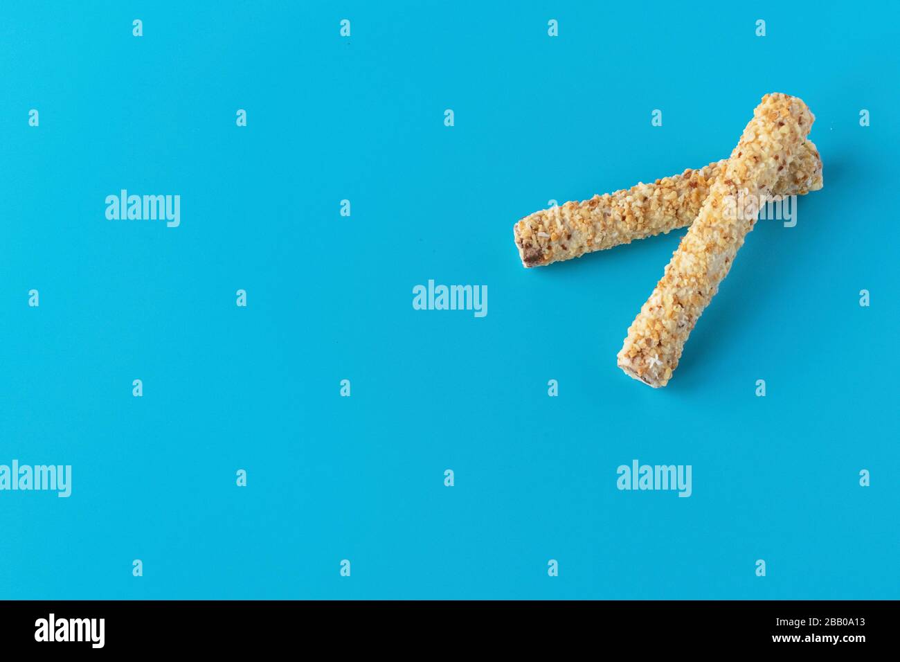 Dessert sucré sur fond bleu. Tubule avec écrous râpés. Cookies, gaufres pour le thé Banque D'Images