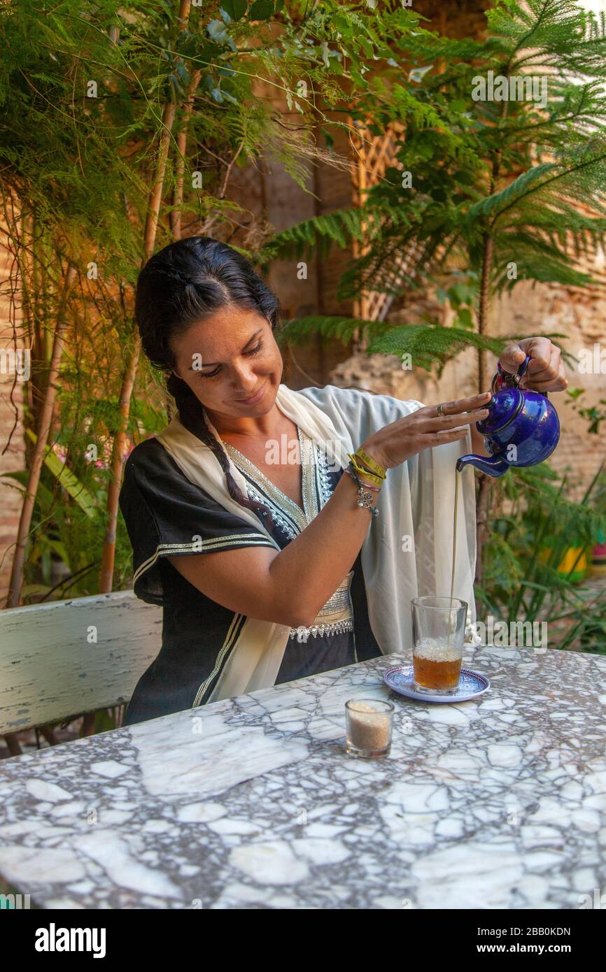 Fes, Maroc: Jeune femme qui verse du thé dans un jardin Banque D'Images