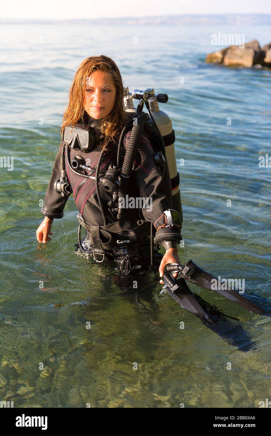 Une femme instructeur de plongée sous-marine debout dans l'eau portant un  costume sec, un réservoir double et des palmes de maintien Photo Stock -  Alamy