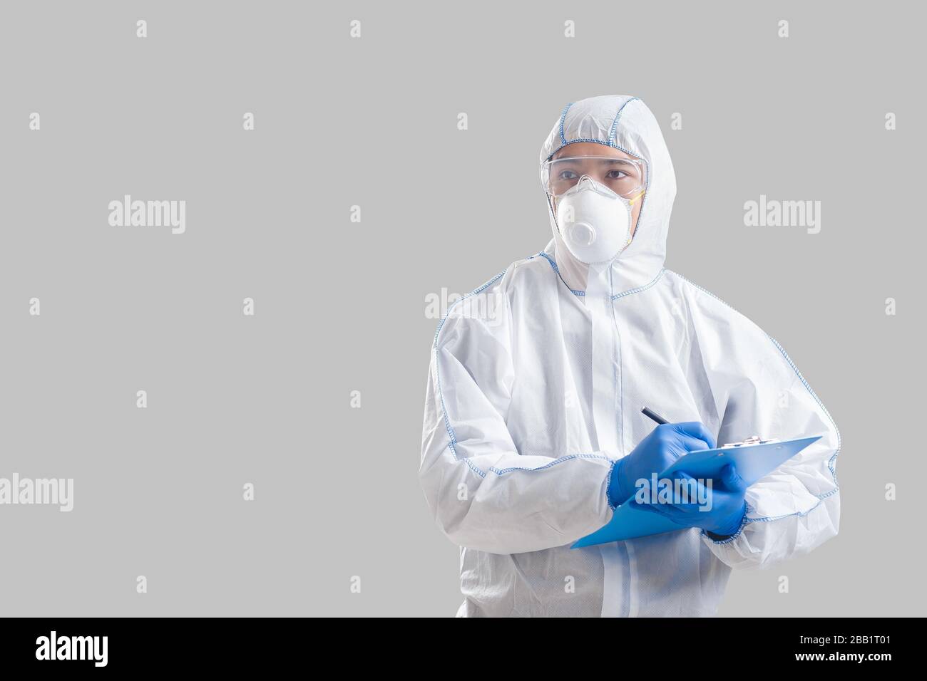 L'homme asiatique dans un costume de protection écrit des données sur le coronavirus Banque D'Images