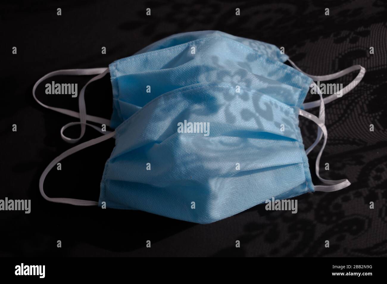 Utilisé deux masques médicaux jetables bleu clair sur fond noir sombre contre le virus covid-2019. Concept de soins de santé, quarantaine, arrêt Banque D'Images