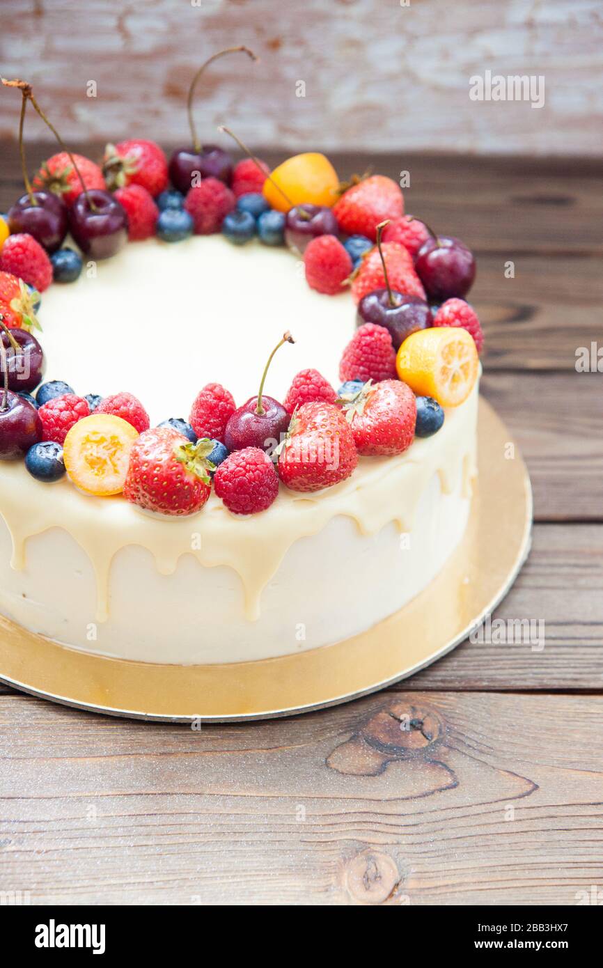 Cheesecake au chocolat blanc, baies fraîches, fraises, cerises, bleuets et framboises sur fond de bois. Dessert d'été. Banque D'Images