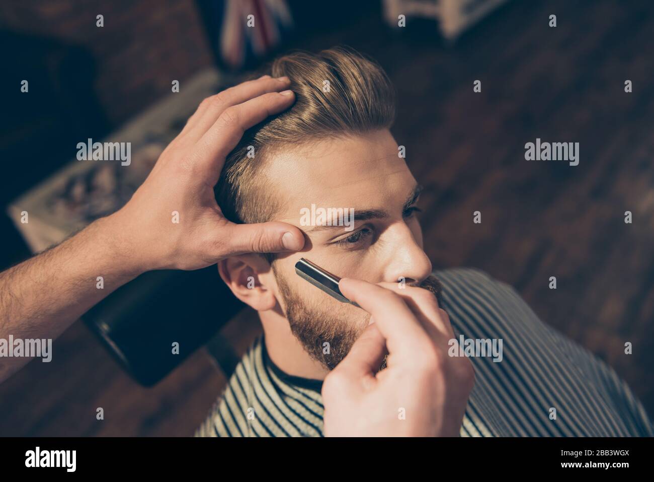 Gros plan sur le travail d'un coiffeur pour un jeune homme blond séduisant  au salon de coiffure. Il fait le styling de sa barbe, la rasant avec droit  Photo Stock - Alamy