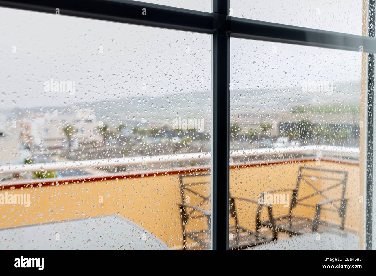 Des gouttes de pluie sur la fenêtre donnant sur le village de Playa San Juan, Tenerife, îles Canaries, Espagne. Banque D'Images