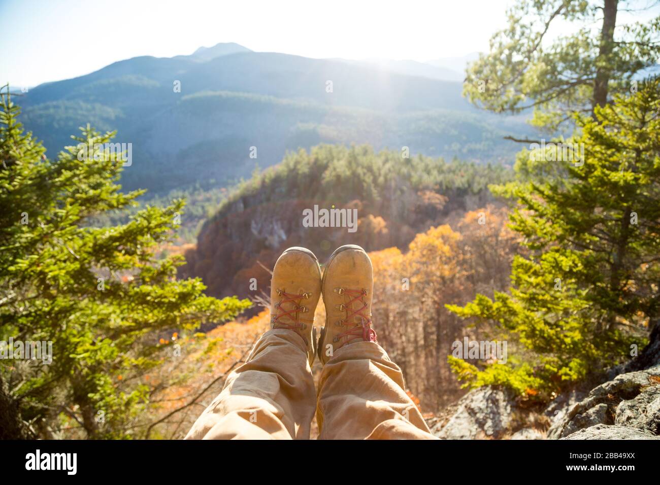 Un randonneur repose ses bottes sur le bord d'un sommet de montagne. Banque D'Images Un randonneur repose ses bottes sur le bord d'un sommet de montagne. Banque D'Images
