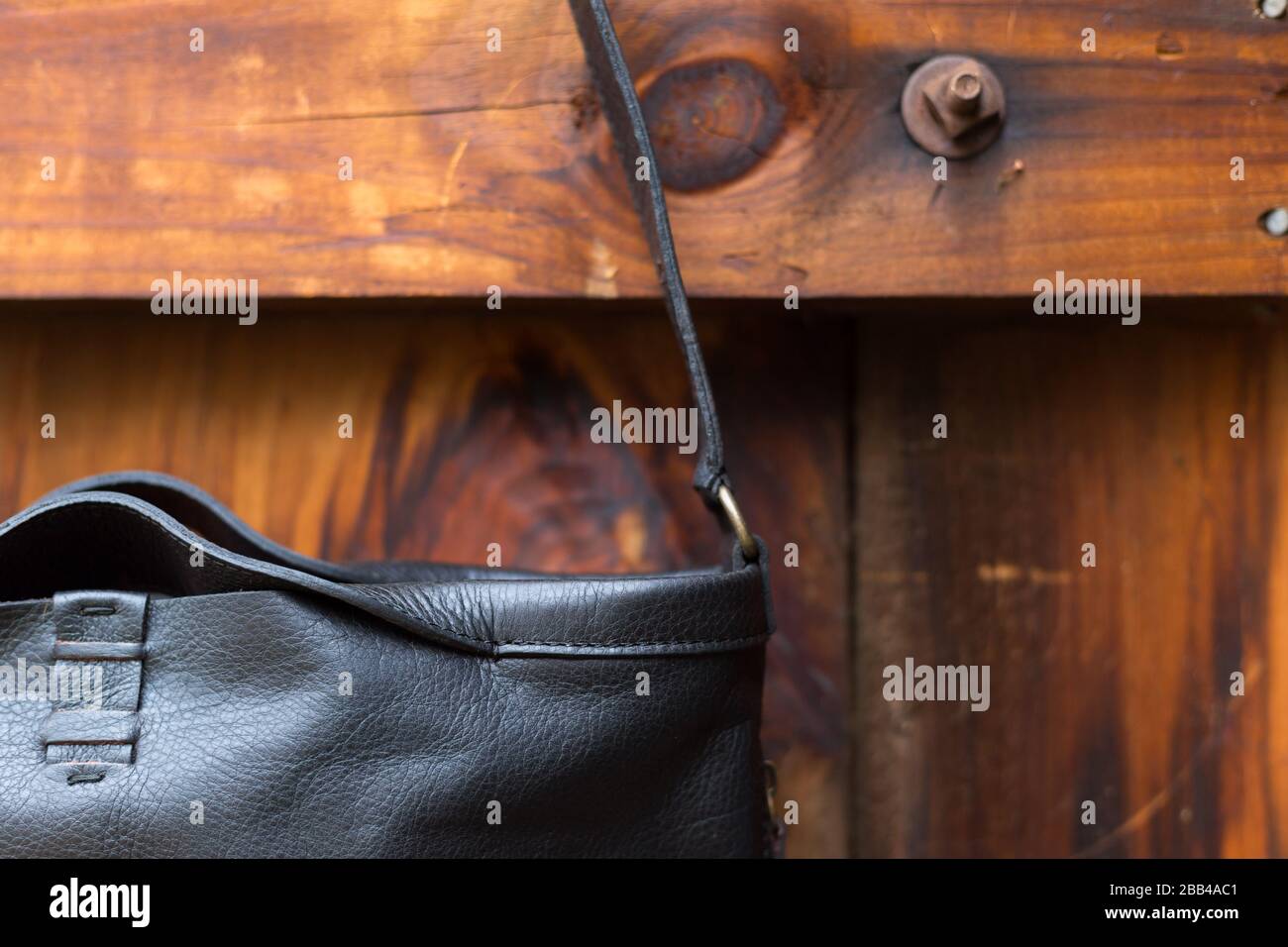 Le sac à main en cuir noir se trouve sur une porte de grange Banque D'Images Le sac à main en cuir noir se trouve sur une porte de grange Banque D'Images