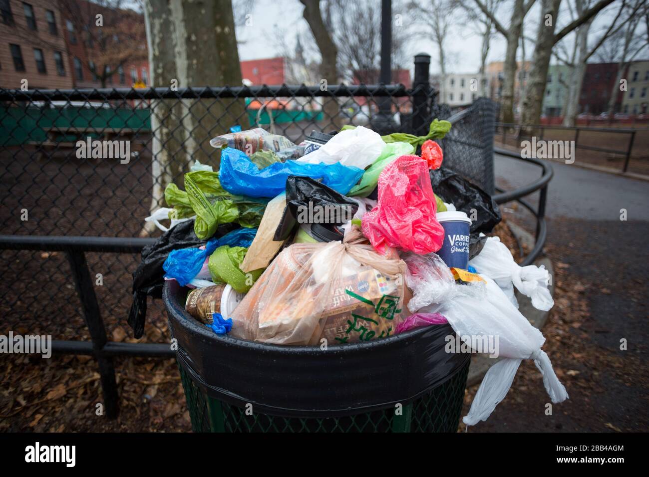 Une poubelle déborde de de déchets plastiques dans le parc pour chiens Banque D'Images Une poubelle déborde de de déchets plastiques dans le parc pour chiens Banque D'Images