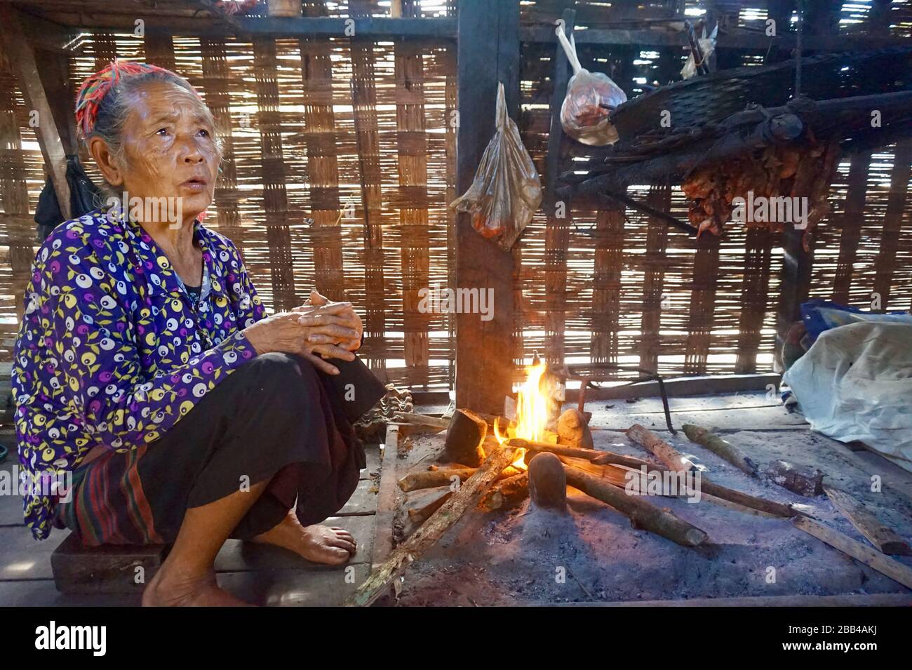 Vieille femme tribale de la zone de conservation de Nam Ha dans la cuisine avec feu ouvert Banque D'Images