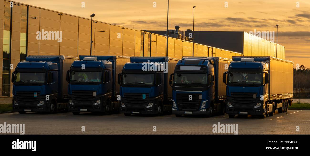 Concept de transport routier. Camions dans le parking sous l'entrepôt à la  lumière du soleil couchant Photo Stock - Alamy