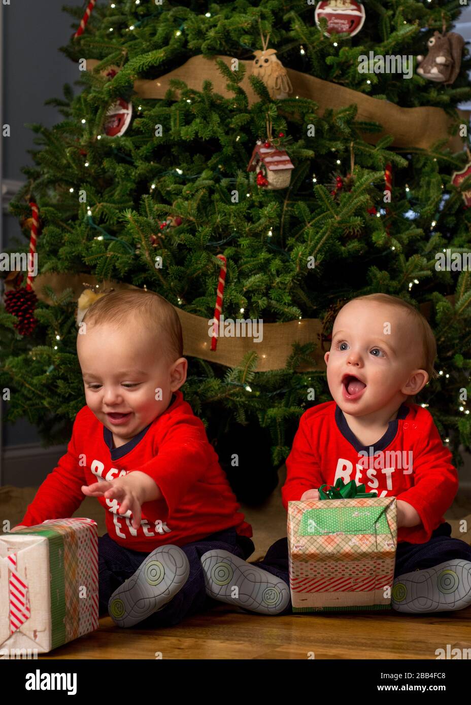 Deux bébés garçons avec cadeaux de Noël sous l'arbre. Banque D'Images
