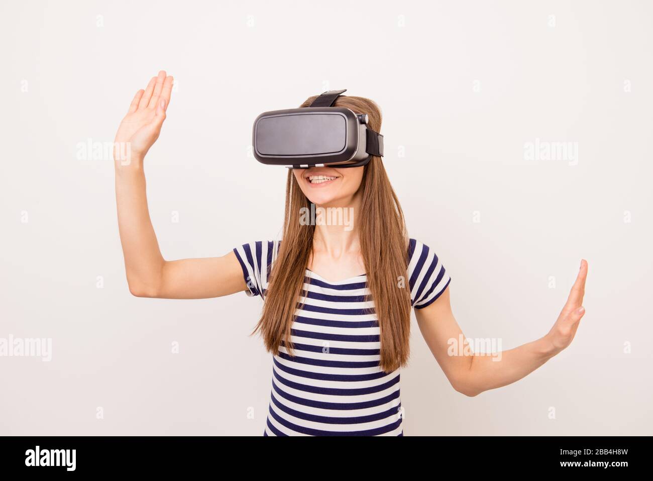 Une jeune fille souriante portant des lunettes de protection pour la vision virtuelle et gestuelle avec ses mains Banque D'Images