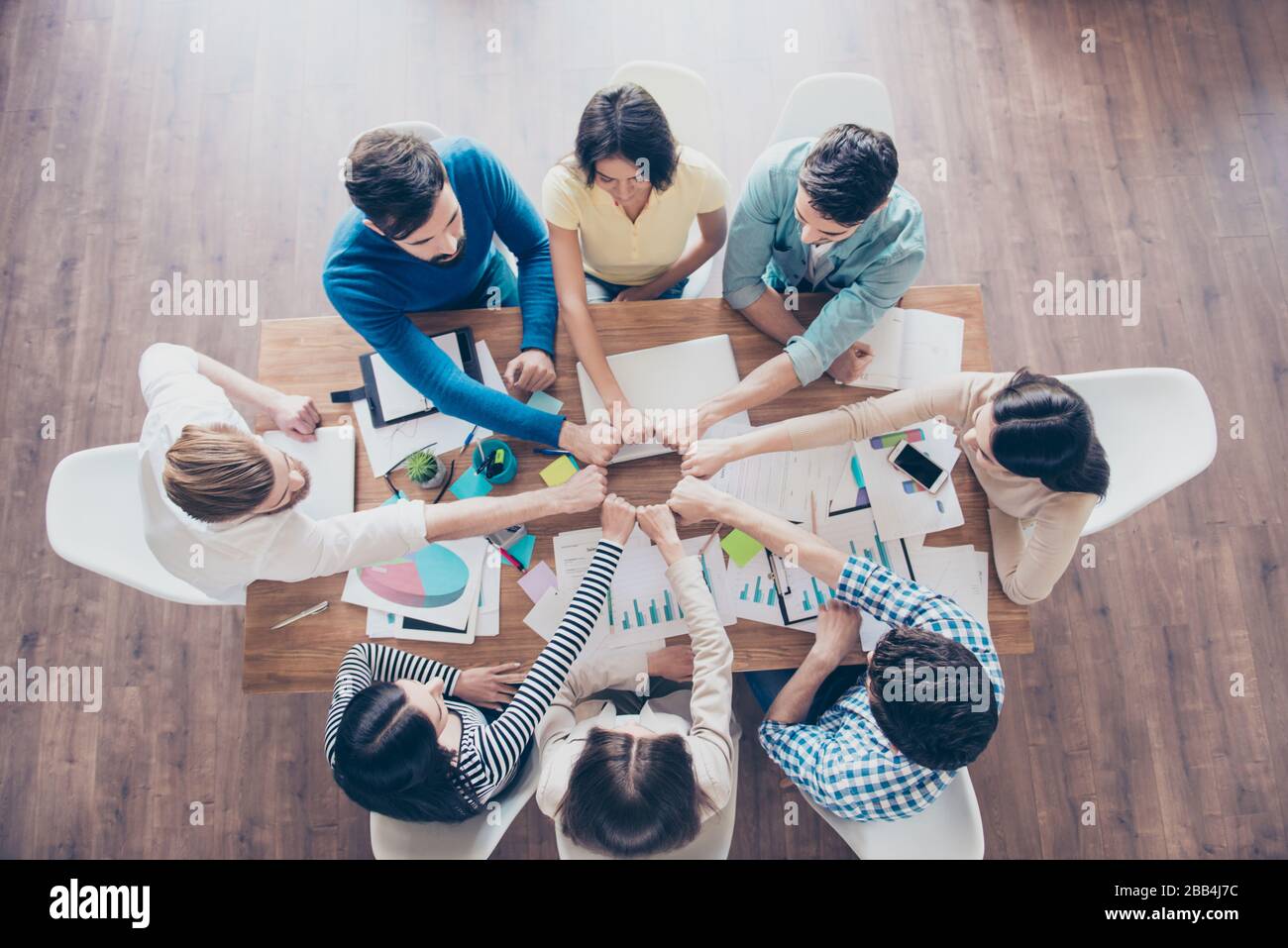 Faites le plein de collègues en plaçant leurs poings en rond sur la table avec des travaux au bureau. Confiance, amitié, unité, coopération Banque D'Images