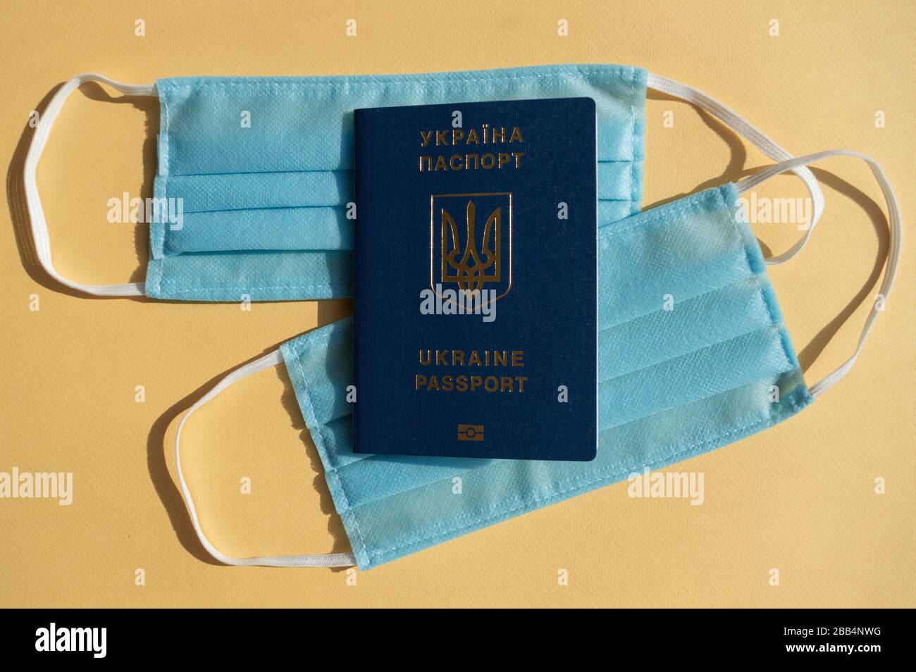 Passeport de l'Ukraine sur deux masques médicaux bleu clair sur les arrière-plans jaune vif contre le virus covid-2019. Concept de soins de santé, arrêter le coronavirus. Banque D'Images