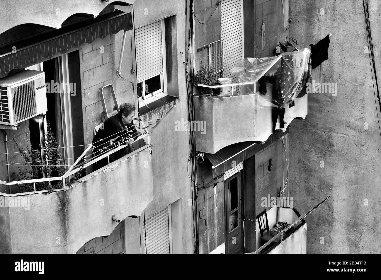 Une vieille femme regarde brièvement de son balcon pendant la deuxième semaine du verrouillage du coronavirus à Barcelone, en Espagne. Banque D'Images
