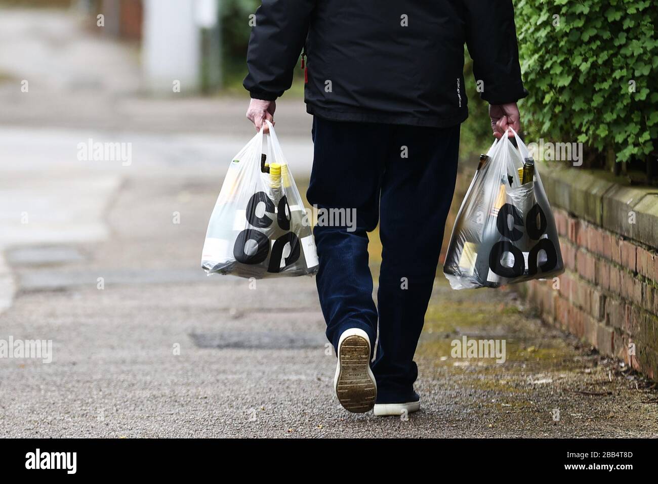 Un homme porte ses magasins à West Bridgford, Nottingham alors que le Royaume-Uni continue de se maintenir en place pour aider à freiner la propagation du coronavirus. Banque D'Images