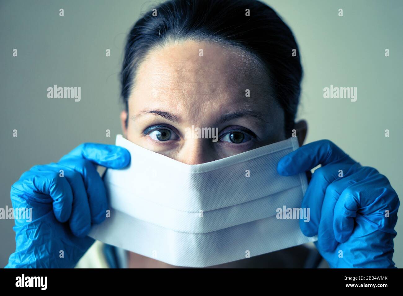 portrait d'une femme médecin portant un masque de protection et regardant la caméra se poser sur fond blanc. Banque D'Images