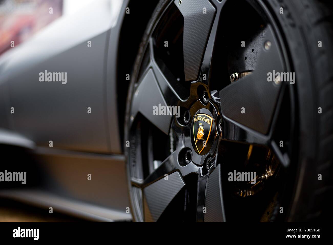 Gros plan sur le badge Lamborghini sur l'impressionnante roue avant d'une super voiture Lamborghini Huracan noir mat. Banque D'Images
