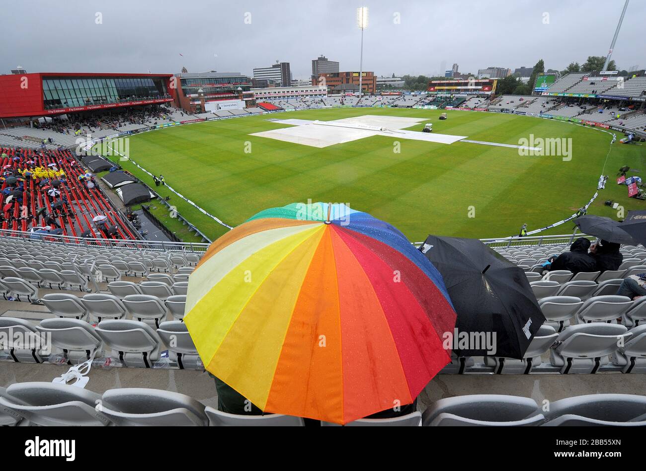 Les fans s'abriter sous les parasols pendant que la pluie s'arrête de jouer Banque D'Images