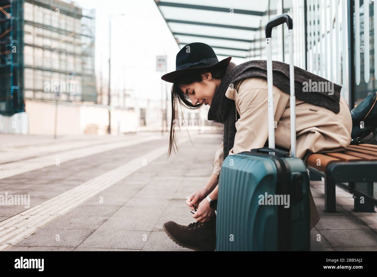 Jeune fille touristique à lacets chaussures tout en étant assis à un arrêt de transport public Banque D'Images