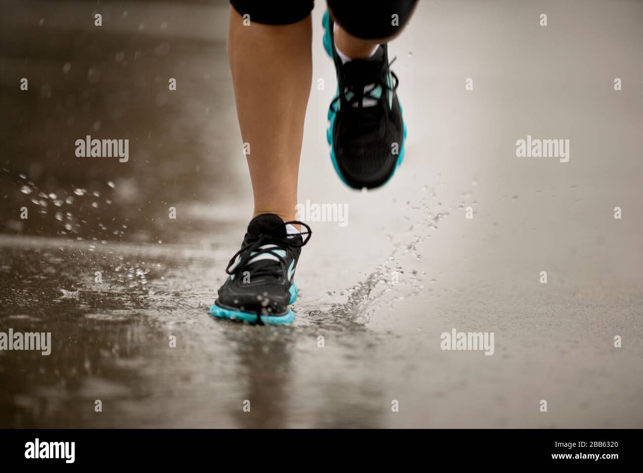 Young woman jogging dans une rue résidentielle de la pluie. Banque D'Images