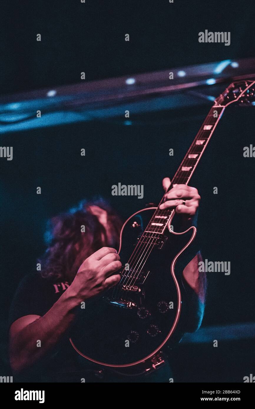 Un homme jouant de la guitare sur scène. Fond sombre, spots. Banque D'Images