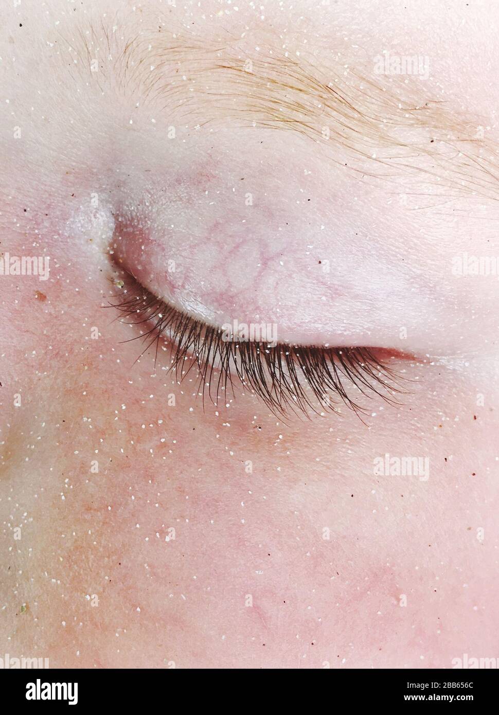 Gros plan de sable autour de l'œil fermé d'un bébé Banque D'Images