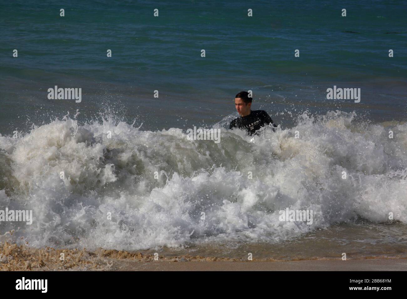 Plage de Grand Anse Grenada Teenage Boy nager en mer dans la vague de crashing Banque D'Images