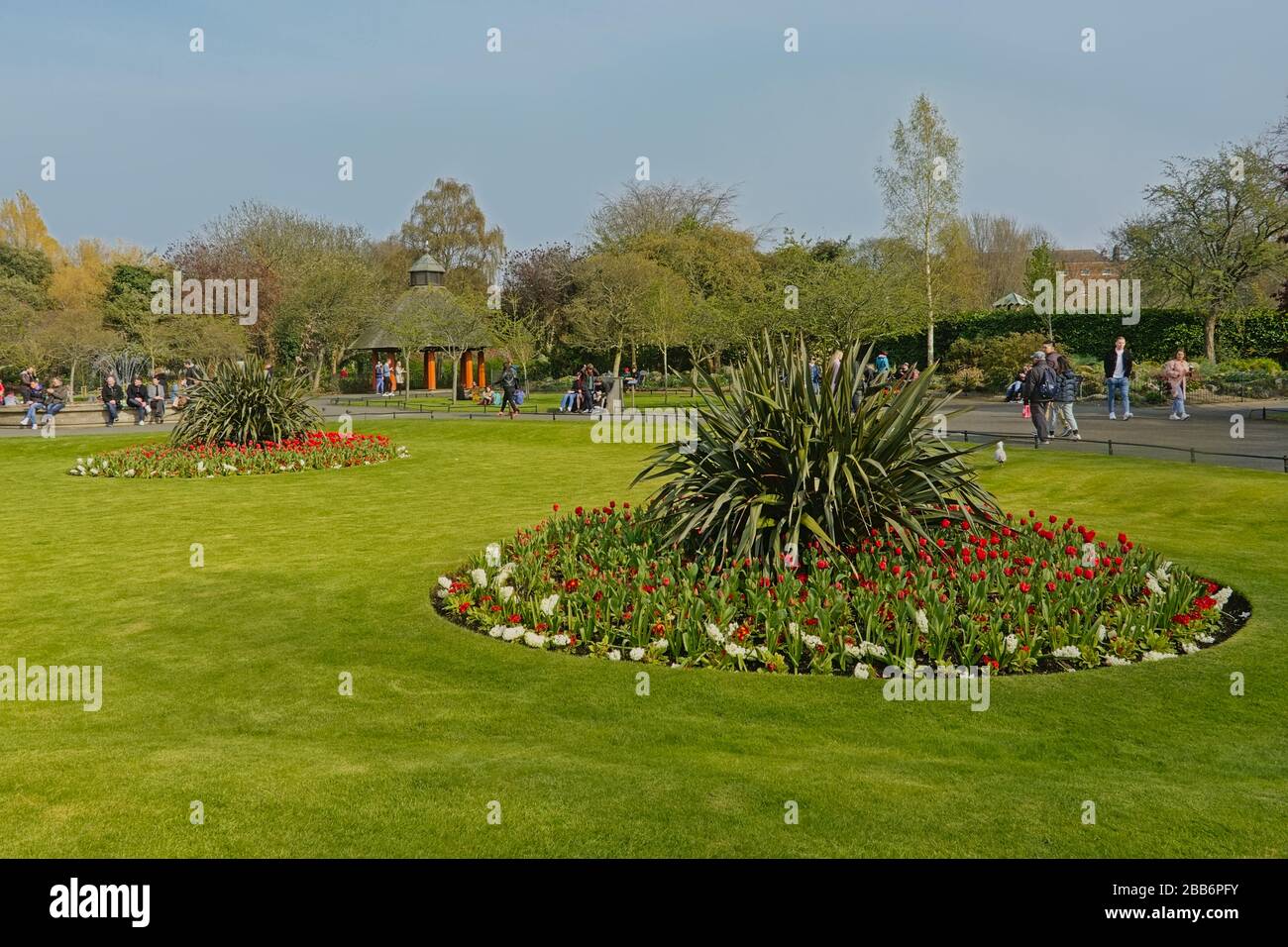 Pelouse avec lit de fleurs et personnes pentant autour d'une fontaine dans le parc vert de Saint Stephen, Dublin Banque D'Images