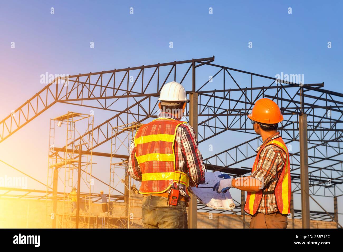 Deux travailleurs de la construction sur un chantier de construction regardant les plans, Thaïlande Banque D'Images