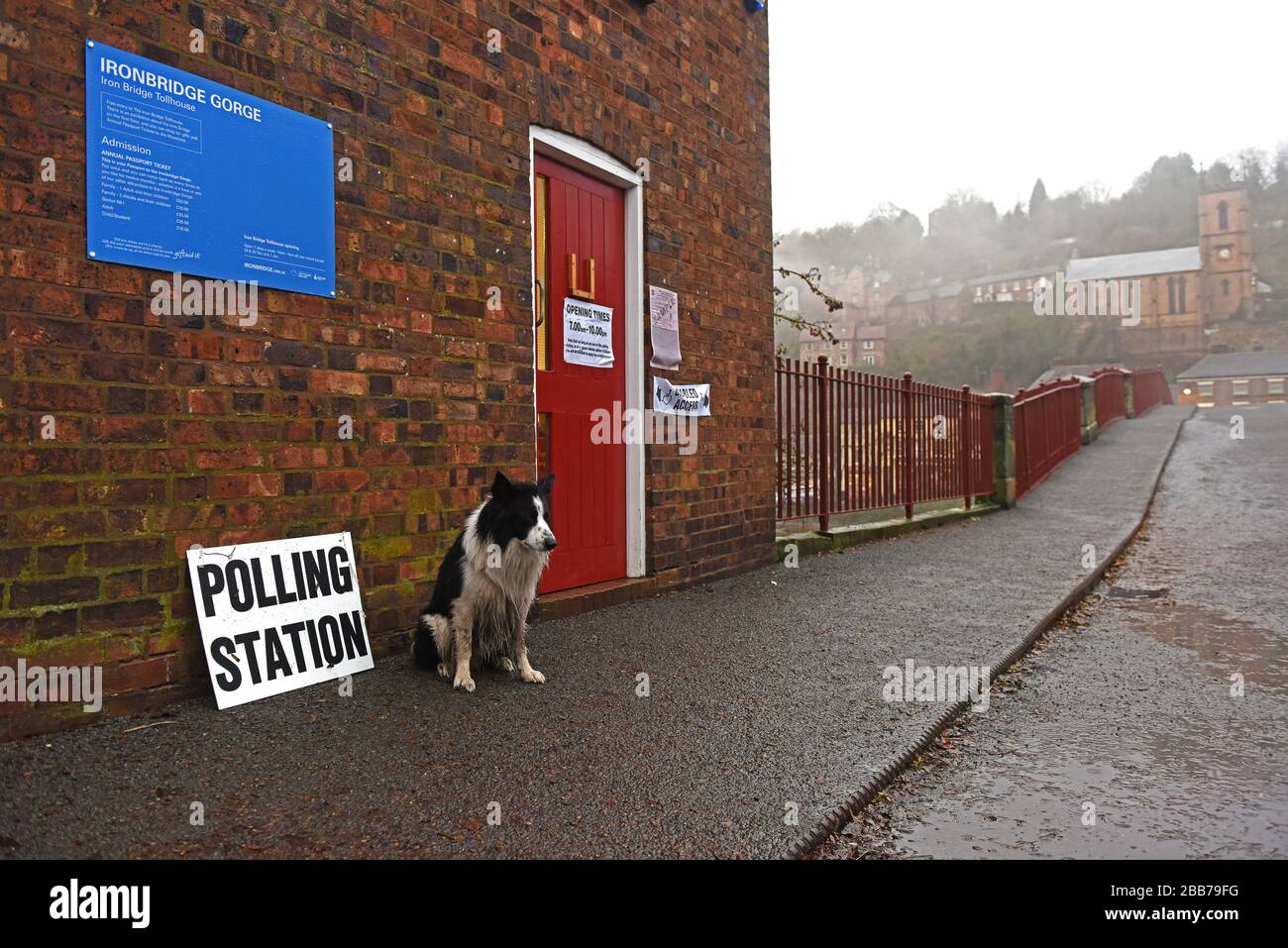 Voter à l'élection générale 2019 à Coalbrookdale alors que le chien attend sous la pluie. Banque D'Images