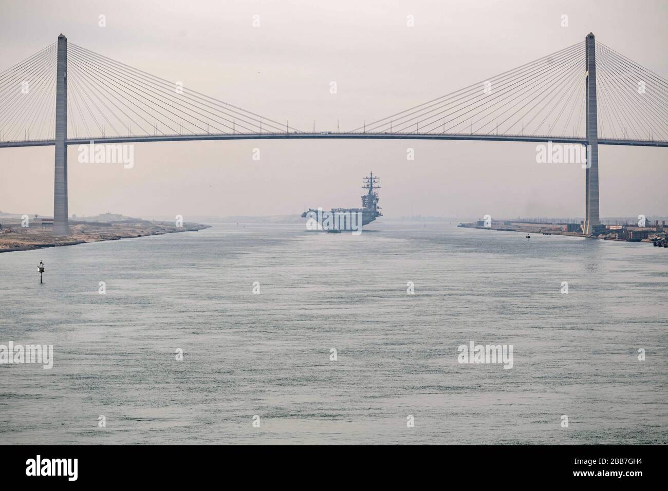 Le porte-avions de classe Nimitz de la marine américaine USS Dwight D. Eisenhower traverse sous le pont de paix de Moubarak lorsqu'il transite le canal de Suez le 9 mars 2020 à El Qantara, en Egypte. Banque D'Images