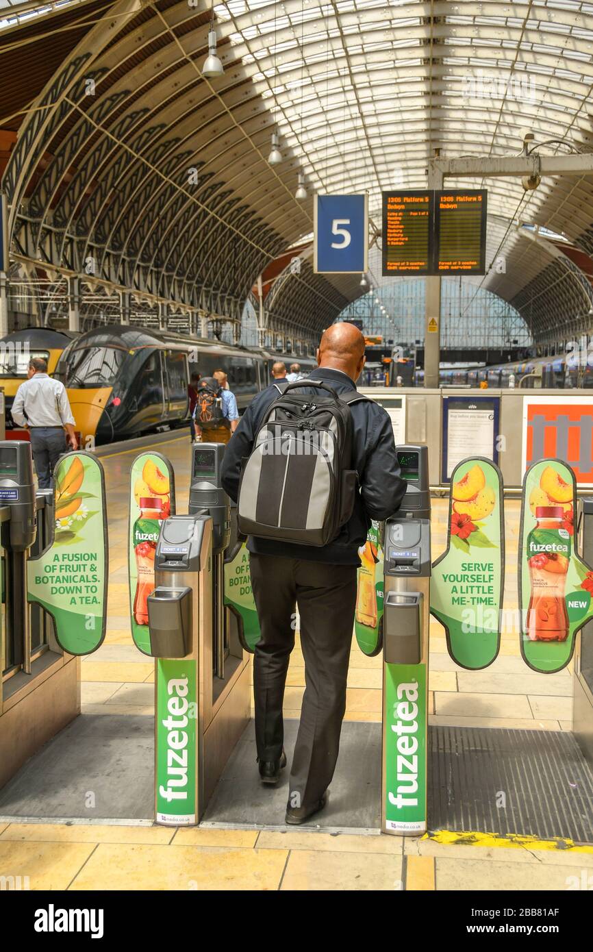 LONDRES, ANGLETERRE - JUILLET 2018 : voyageur ferroviaire passant par une barrière automatique de billet sur le parcours de la gare de Paddington à Londres Banque D'Images