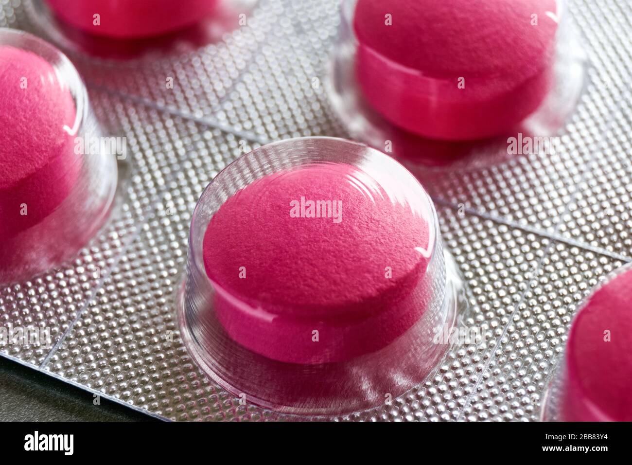 Pilules sous blister. Macro gros plan de pilules médicales rouges dans la plaquette thermoformée sur un fond gris pour une utilisation comme fond médical ou pharmaceutique. Banque D'Images