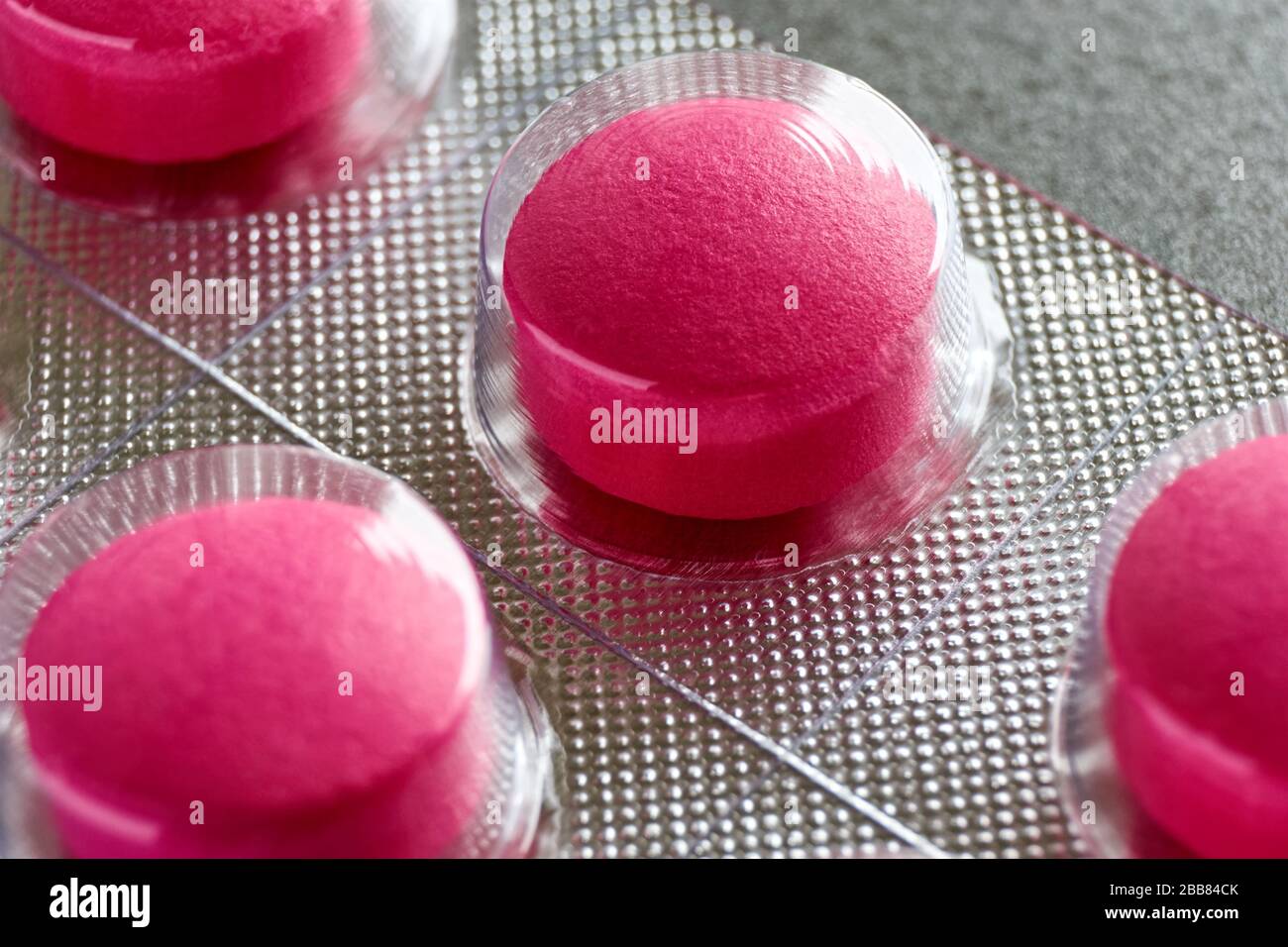 Pilules sous blister. Macro gros plan de pilules médicales rouges dans la plaquette thermoformée sur un fond gris pour une utilisation comme fond médical ou pharmaceutique. Banque D'Images