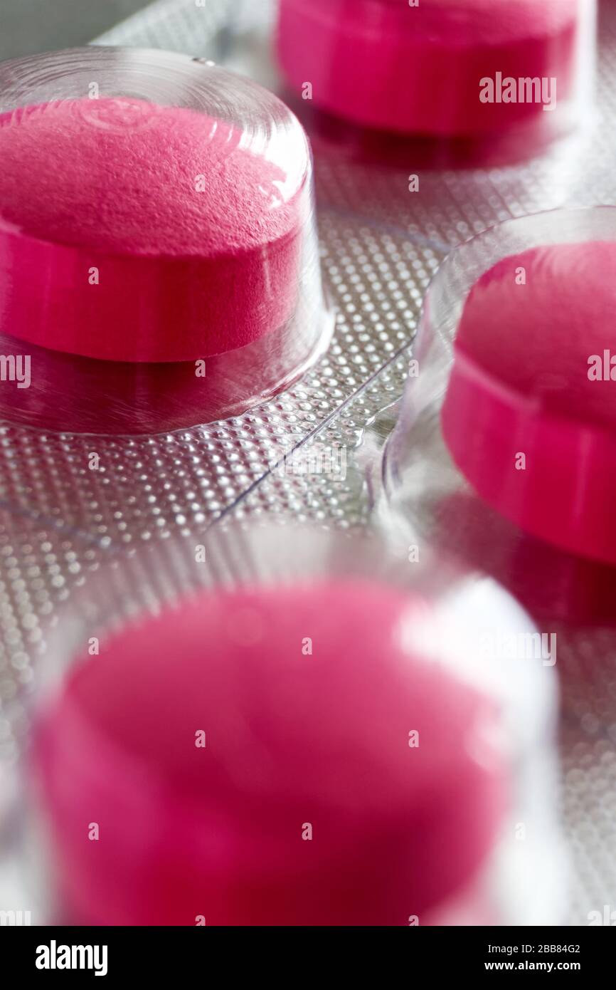 Pilules sous blister. Macro gros plan de pilules médicales rouges dans la plaquette thermoformée sur un fond gris pour une utilisation comme fond médical ou pharmaceutique. Banque D'Images