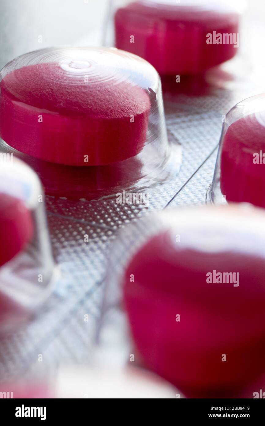 Pilules sous blister. Macro gros plan de pilules médicales rouges dans la plaquette thermoformée sur un fond gris pour une utilisation comme fond médical ou pharmaceutique. Banque D'Images