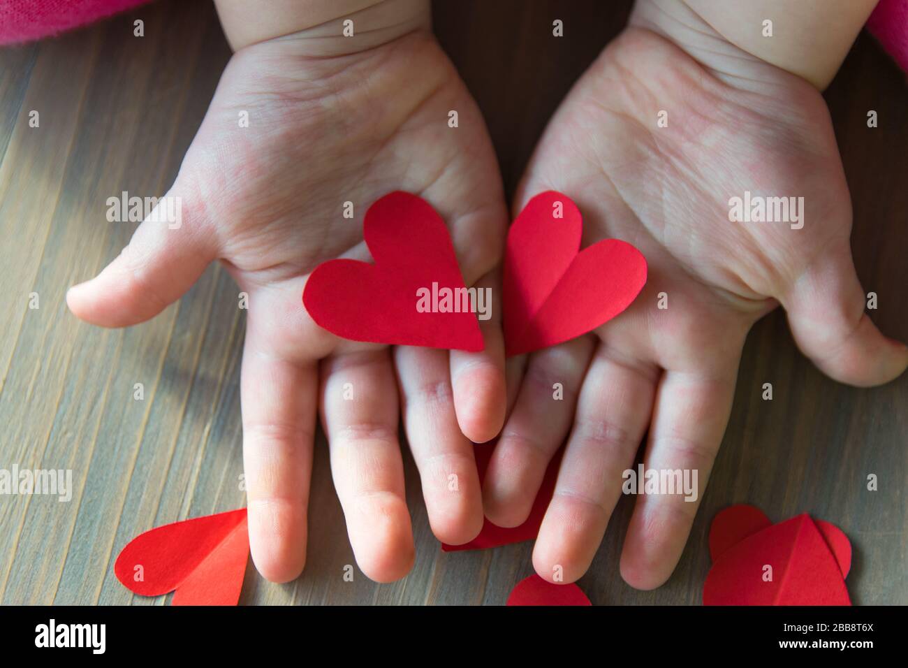 Deux coeurs rouges du papier dans les terres de procréer sur le fond de bois. Signe d'amour. Un cadeau pour la Saint Valentin et la fête des mères. Banque D'Images