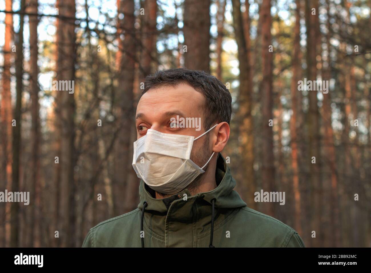 un homme sur une promenade dans une forêt portant un masque chirurgical blanc pendant une quarantaine le soir Banque D'Images