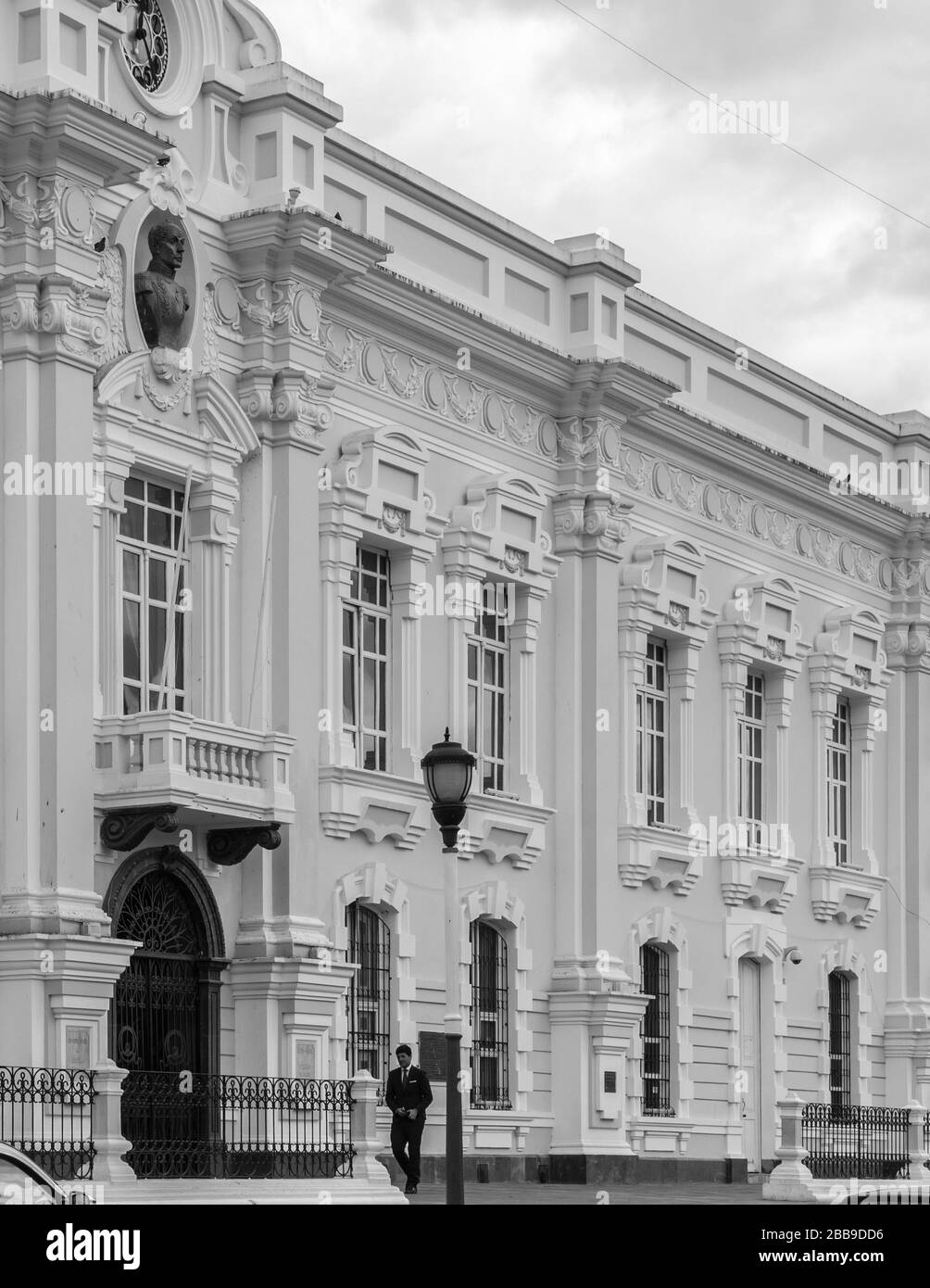 OTAVALO, ÉQUATEUR - 28 JUILLET 2018 : une photo en noir et blanc d'un homme en costume marchant devant la municipalité GAD d'Otavalo. Banque D'Images