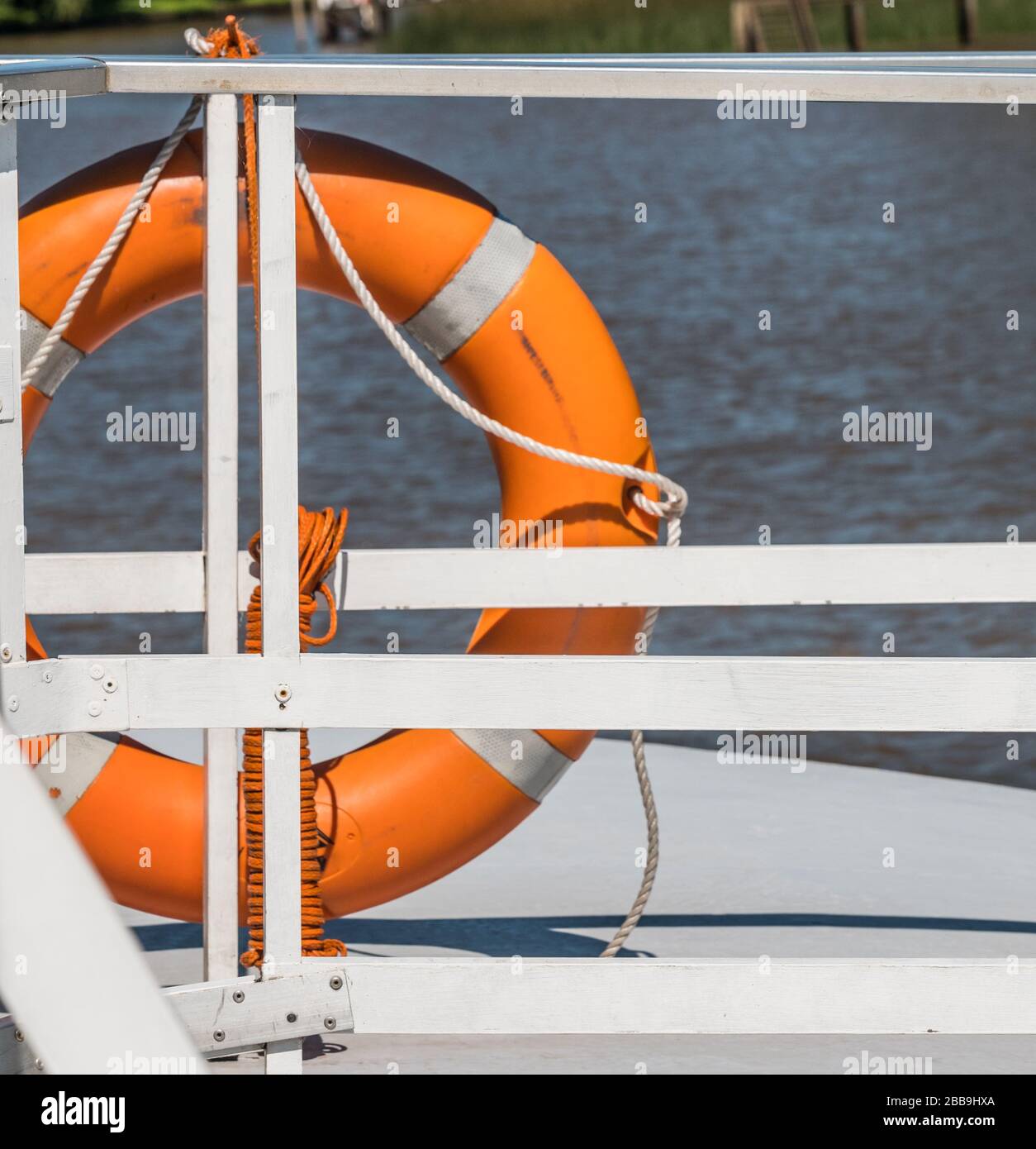 Photo d'un rail de garde sur un bateau avec un garde-vie orange attaché à lui. Banque D'Images