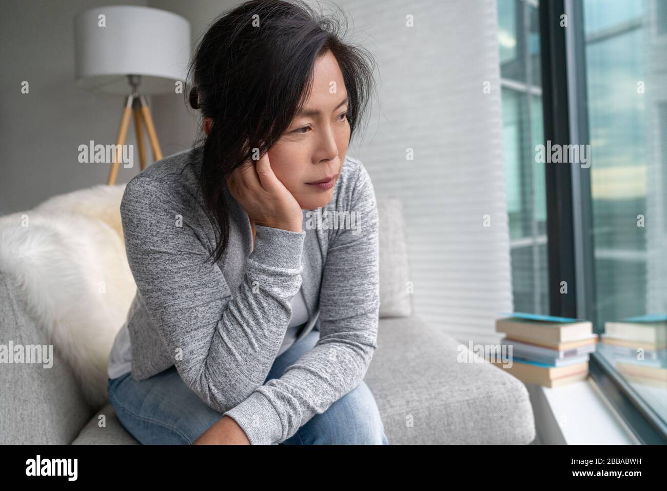 Triste femme asiatique mûre solitaire à la maison isolement quarantaine pour COVID-19 Coronavirus social distancing prévention. Santé mentale, anxiété déprimée pensant la dame chinoise senior. Banque D'Images