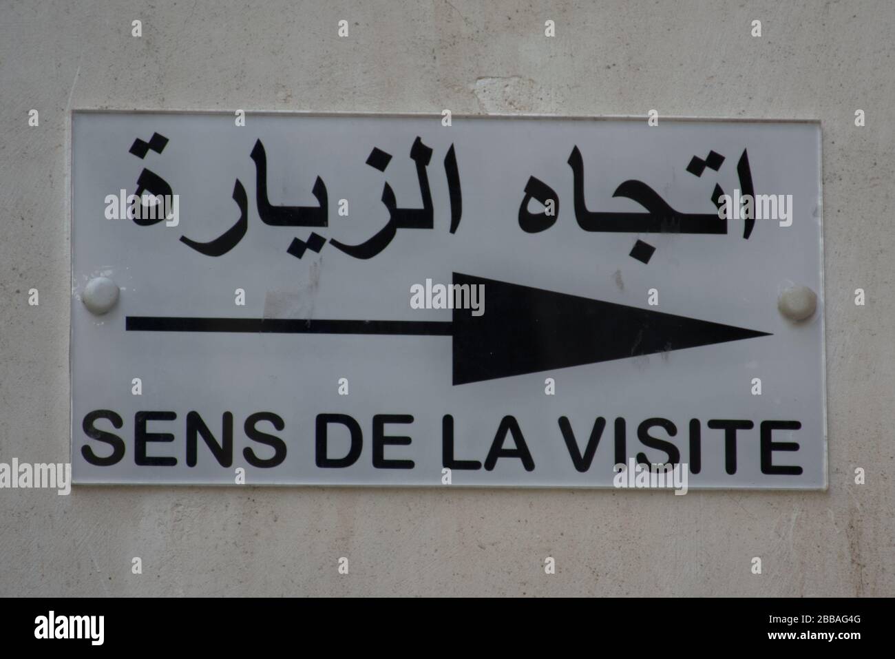 Un signe directionnel en arabe et en français. Le texte traduit des deux langues est -DIRECTION DE LA VISITE-. Banque D'Images