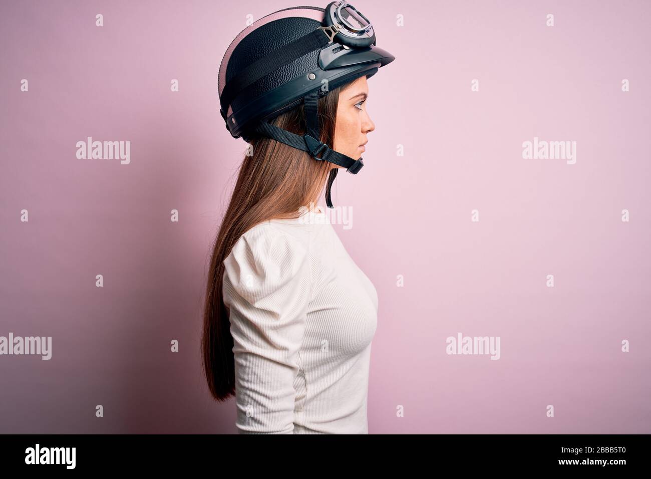 Jeune femme moto belle avec yeux bleus portant un casque moto sur fond rose  regardant sur le côté, se détendre profil pose avec le visage naturel et c  Photo Stock - Alamy