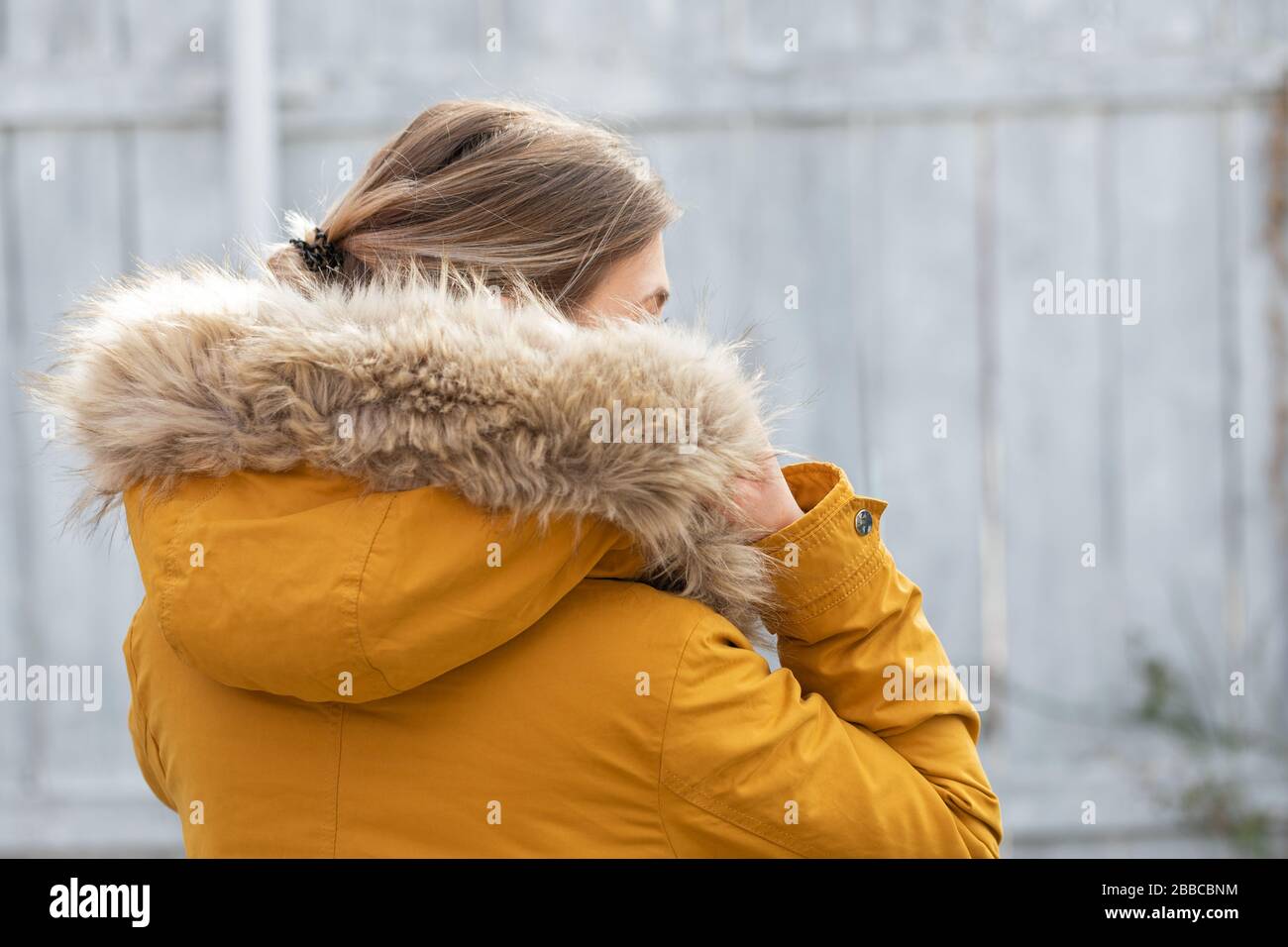 Vue arrière de la femme portant une veste parka à fourrure jaune devant un  fond gris en bois Photo Stock - Alamy
