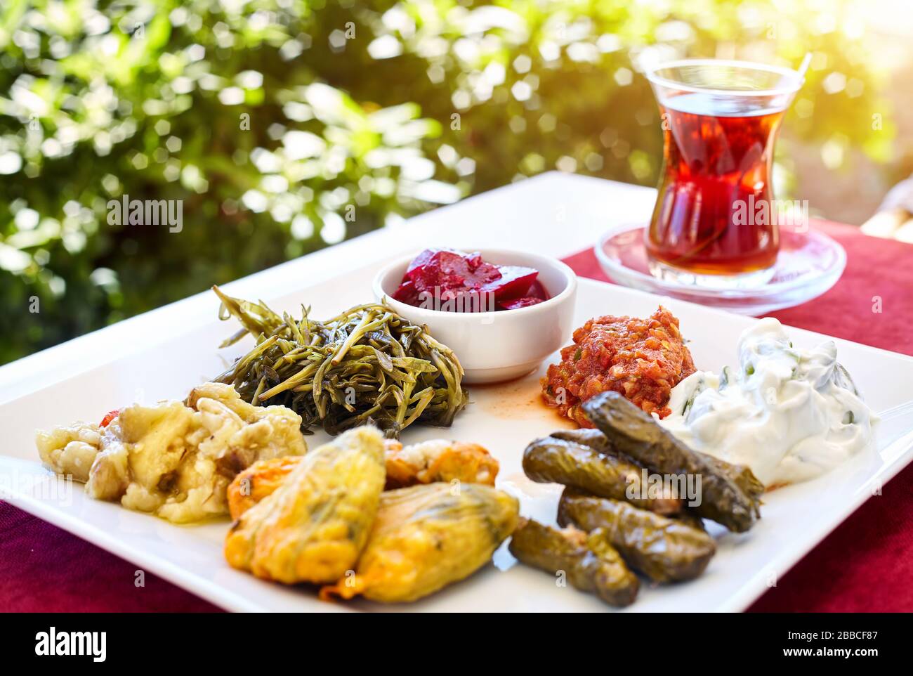 Du thé turc et des plats végétariens au restaurant meze démarreur en verre sur la table rouge en Turquie Banque D'Images